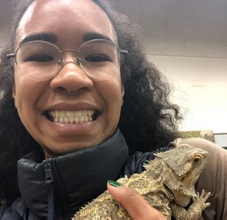 close up photo of geologist Pinkie Young holding a bearded dragon reptile while smiling into the camera