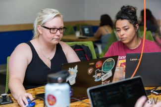 photo of two women working on computer 