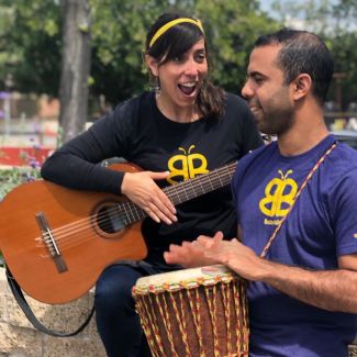 photo of Baila Baila band members Isa playing a guitar and Rico playing a drum