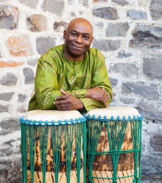 color photo of Onye standing up behind two drums