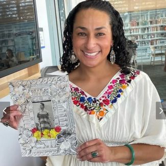 Rachel Palacios holding a repujado framing a picture of Frida Kahlo