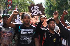 A photograph of dozens of young Black teenagers marching in a protest with signs that read "Black Lives Matter"