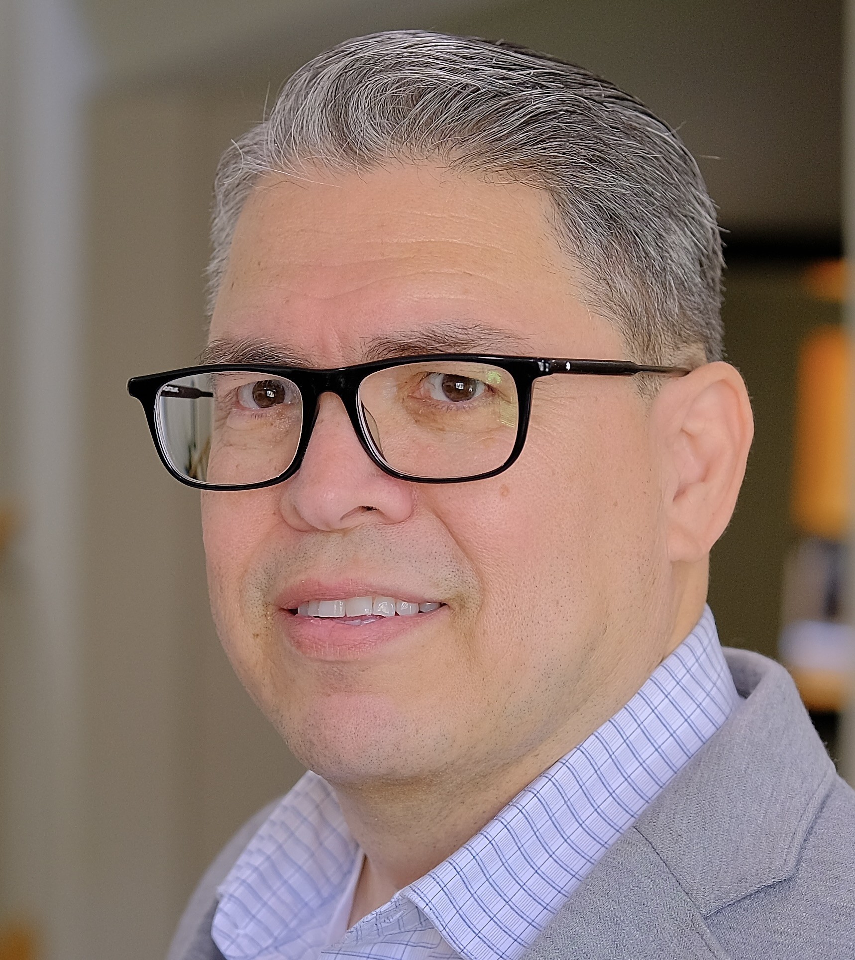 Headshot of artist Alberto Ledesma, siting in profile facing left