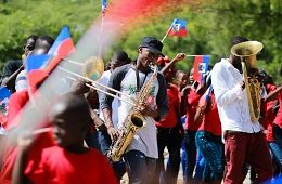 photo of people playing instruments while waving the flag of Haiti; photo by Bailey Torres