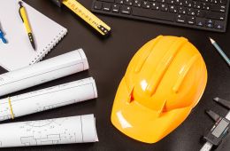 photo of yellow hard hat, blueprints, ruler and computer keyboard