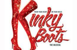 Bright red thigh high boots in the shape of a K to begin spelling the words "Kinky Boots" 