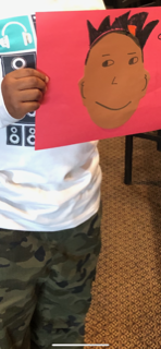 African American child holding self-portrait made as part of the craft exercise.  