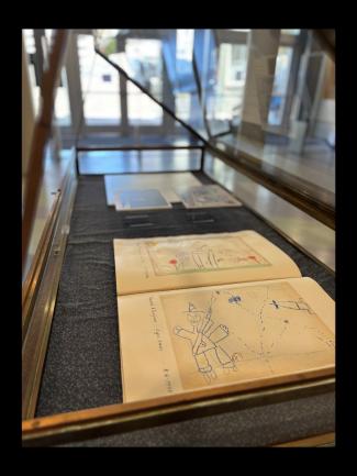 Archival photographs and children's drawings in a display case