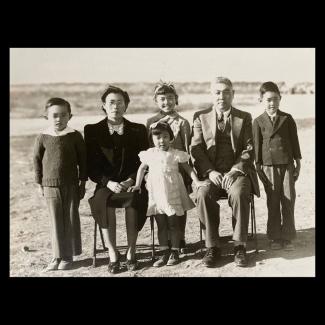 Black and white photograph of a Japanese American family seated for a family portrait in the desert