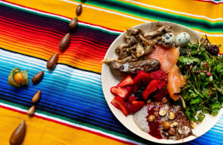 Photo of a decorative line of acorns and a traditional Ohlone meal on a brightly colored striped tablecloth