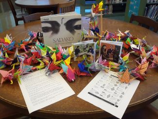 photo of folded cranes along with picture of the book Sadako by Eleanor Coerr with illustrations by Ed Young