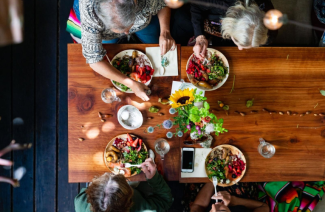 Overhead photo of four people at a large wooden table enjoying Ohlone cuisine