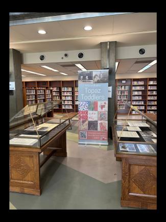 Two display cases and a sign in front of library shelves