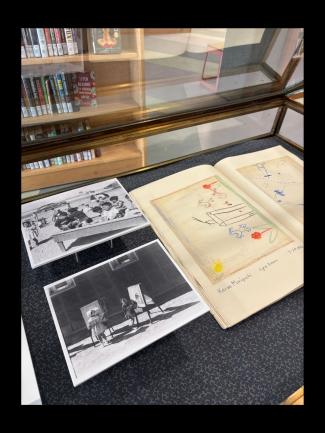 Archival photographs and children's drawings in a display case