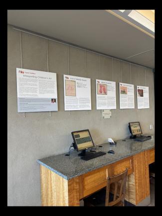Exhibit posters on a wall above some computers