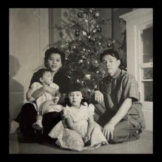 Black and white photograph of a family seated around a Christmas tree