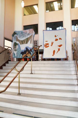 Two quilts being held at the top of the stairs in the Central Library Historic Lobby