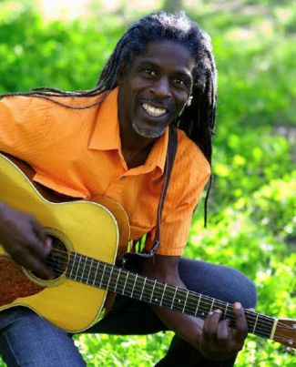 photo of Asheba outside with a guitar. 