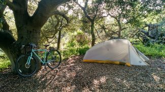 A tent in the woods with a bike nearby.  Photo by Rachel Jacobson