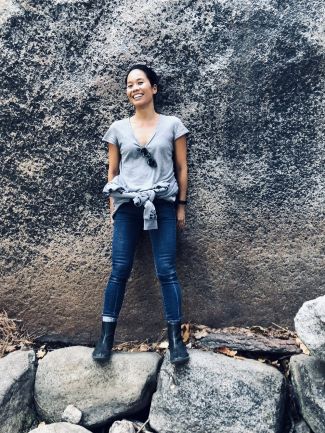 photo of author Bonnie Tsui standing against a big rock while balancing on two smaller rocks