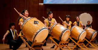 Four smiling taiko drummers with their drums