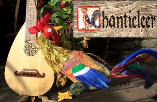 photo of a sign that says Chanticleer and a Rooster puppet sitting alongside what looks to be a mandolin