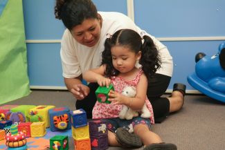 photo of child playing blocks with adult