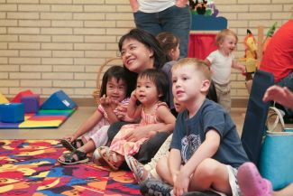photo of children sitting with an adult surrounded by toys