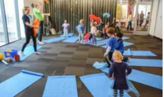 yoga mats in a circle with adults and kids standing, ready to stretch