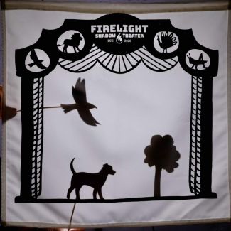 photo of a shadow puppet show with a bird, dog and a tree 