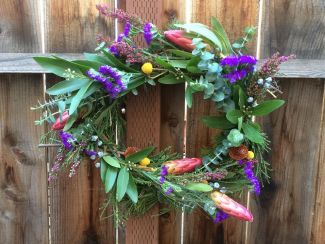 Wreath of leaves and flowers hanging on a wooden fence