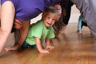 Child crawling under grown-up in a downward-facing dog pose. CC Jessica Lucia https://www.flickr.com/photos/theloushe/3988309695