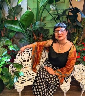 Decolonized Kitchen presenter Maribel Garcia seated with plants