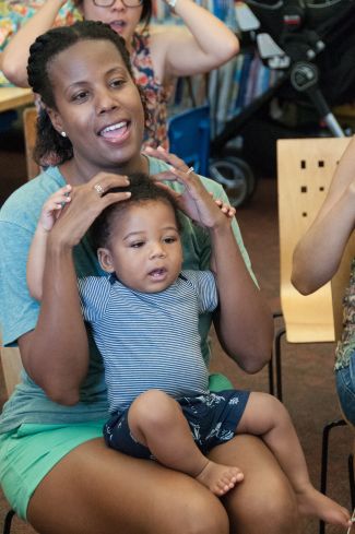 photo of child sitting on mom's lap while mom sings