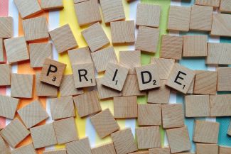 "Pride" in scrabble tiles over a rainbow. 
