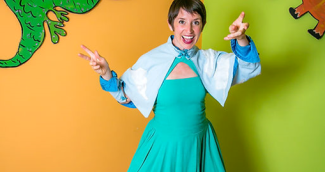 photo of Risa in front of an orange and green wall, wearing a blue dress with a cape