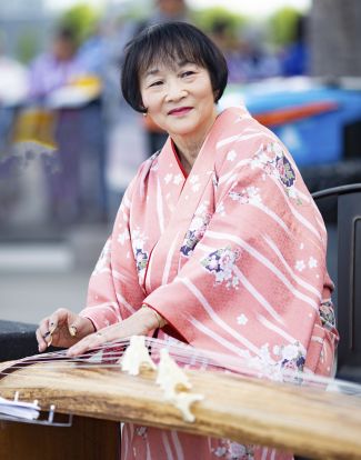 photo of Shirley Kazuyo Muramoto wearing a pink kimono and playing a koto