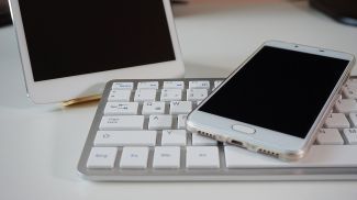 A keyboard and two devices with screens