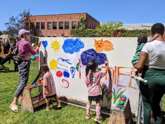 photo of kids outdoors painting on giant wall 