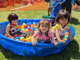 photo of little kids in baby pool ball pit surrounded by colorful plastic balls