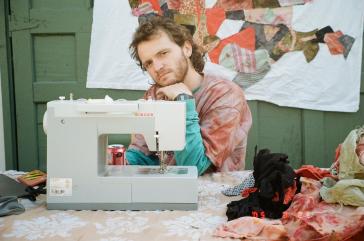 Curator Cordy Joan sitting behind a sewing machine