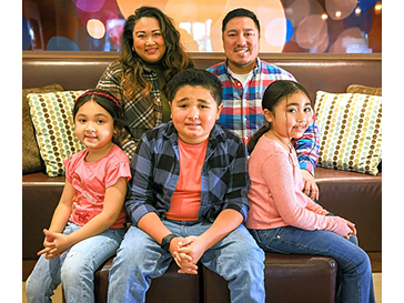 Five family members posing on a couch for a portrait