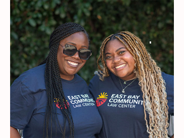 Two people smiling and wearing T-shirts that say East Bay Community Law Center 