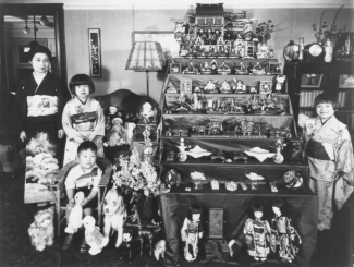 Japanese Children posing with a case of dolls and medals