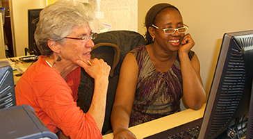 Two smiling women working at a computer