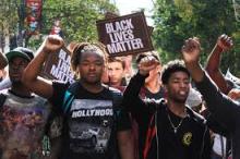 A photograph of dozens of young Black teenagers marching in a protest with signs that read "Black Lives Matter"
