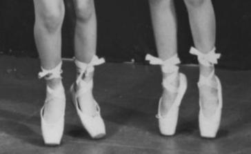 two ballerinas on point shown from knees down